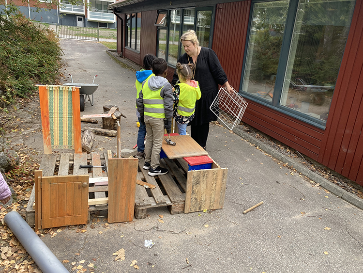 Barnen bygger ett hus tillsammans i snickeristationen på förskolegården.