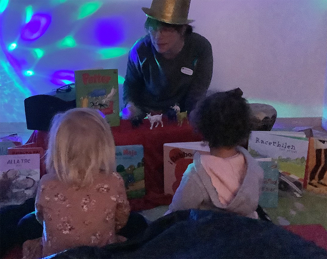 två barn läser bok med pedagog i magiskt rum