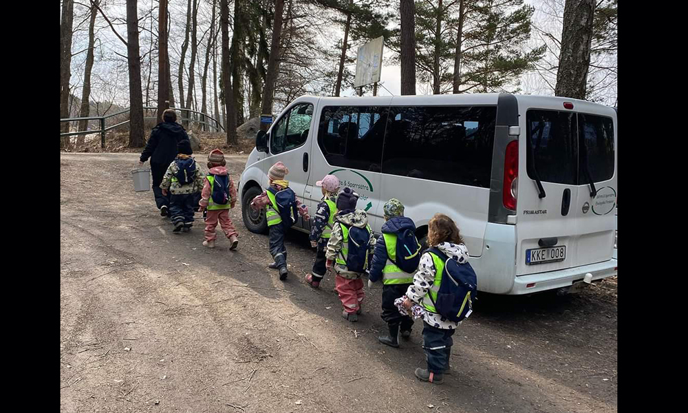 Pedagog och barn på utflykt med minibuss.