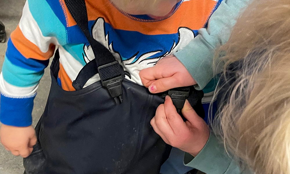 Ett barn som hjälper ett annat barn med kläderna.