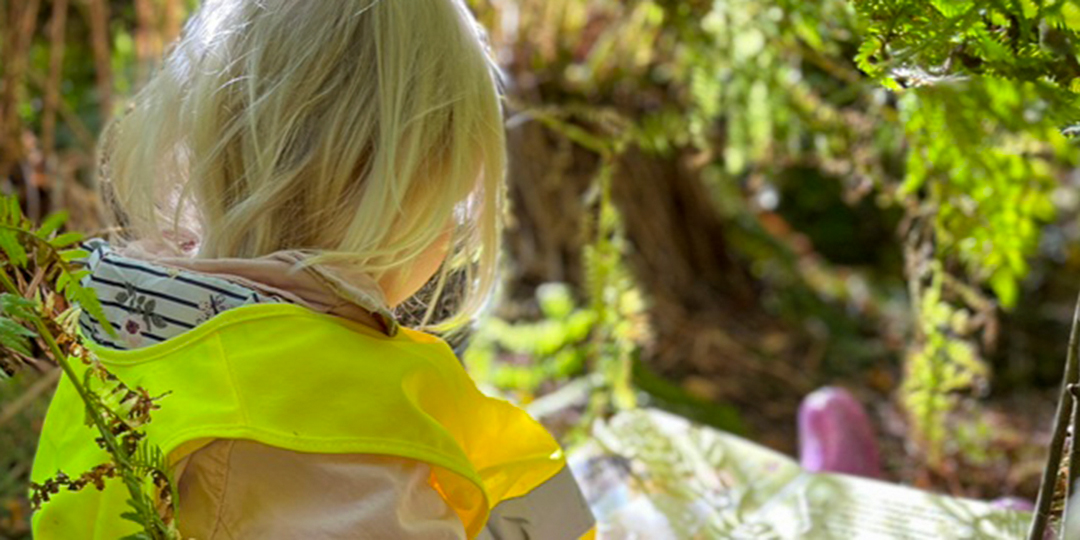 Flicka som läser bok i skogen.