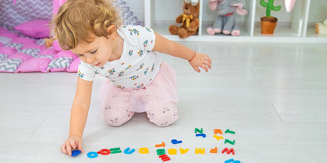 Ett barn som leker med bokstäver på golvet på förskolan.
