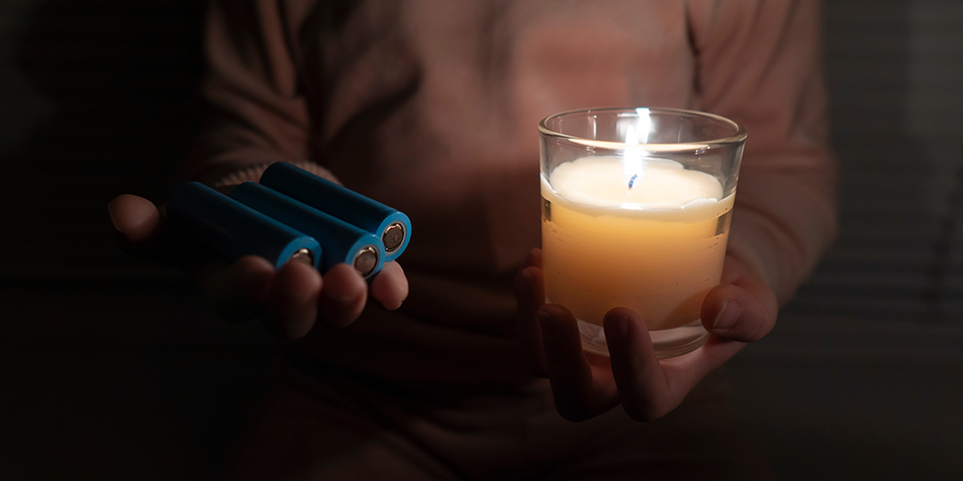 Ett barn i ett mörkt rum håller i ett stearinljus och batterier.
