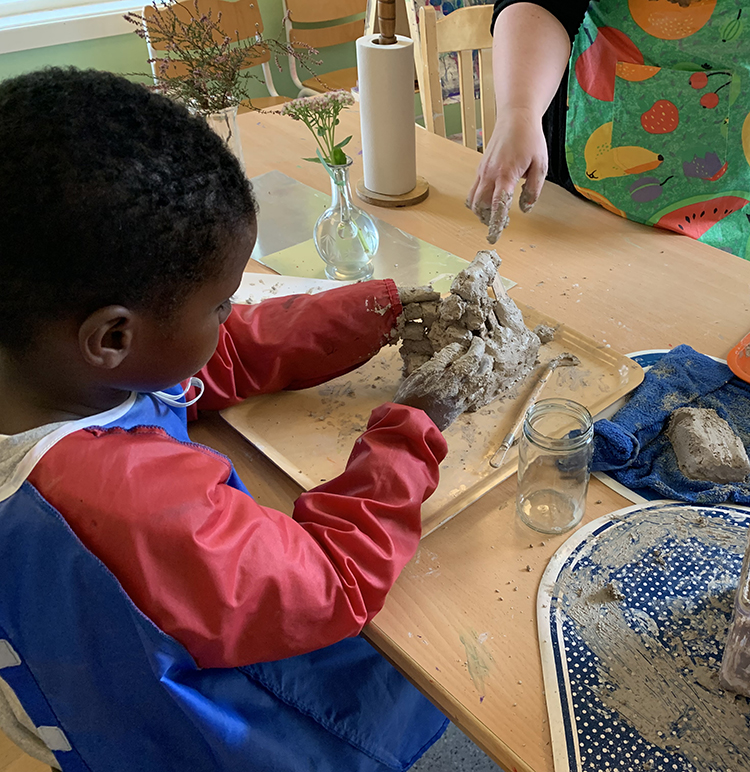 Ett av förskolebarnen arbetar med att konstruera ett hus av lera utifrån sagan De tre små grisarna