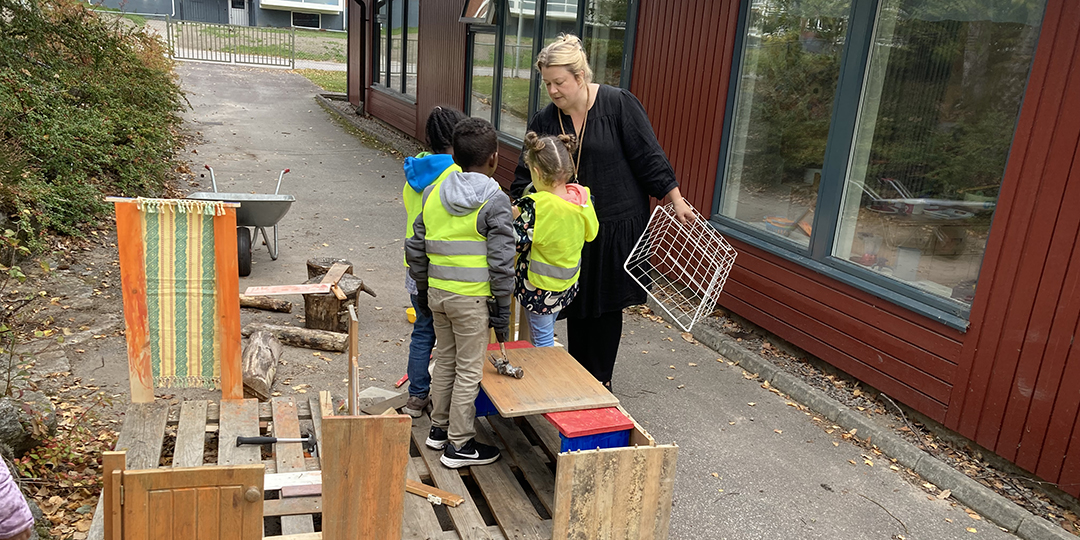Barnen bygger ett hus tillsammans i snickeristationen på förskolegården.