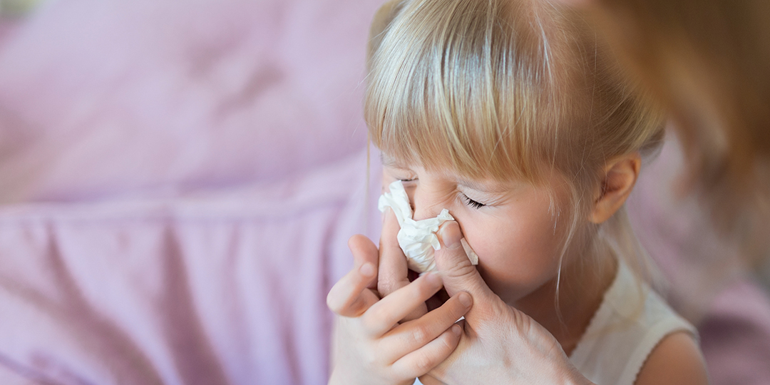 En kvinna snyter sin dotters rinnande näsa.