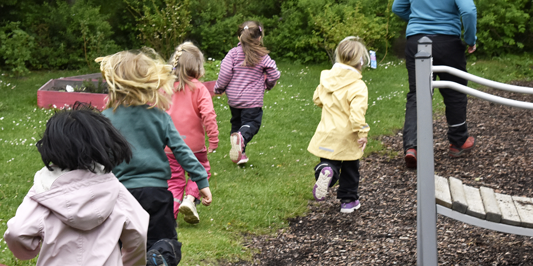 Fem barn och en pedagog på promenad i skogsmiljö.