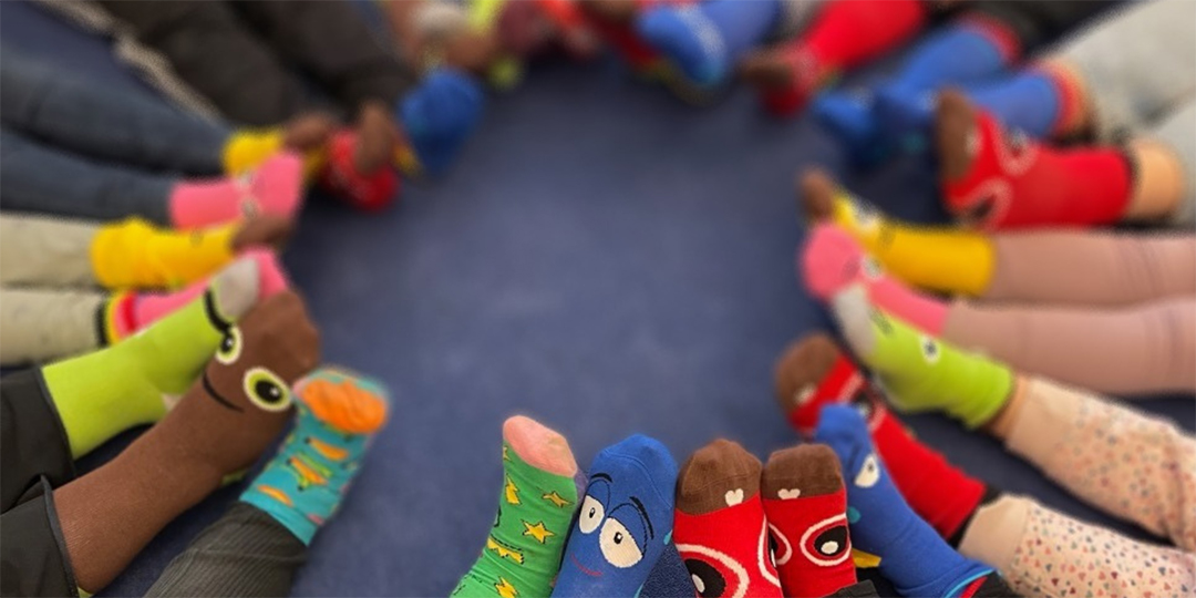 Många barnfötter med strumpor i olika färger och mönster.