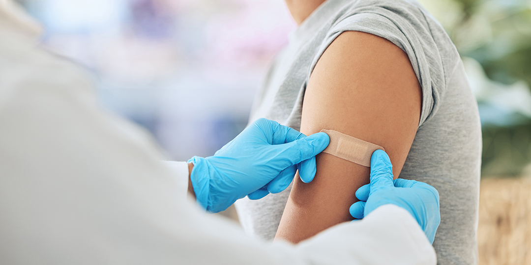 Sjuvårdspersonal sätter på ett plåster på en kvinnas överarm.