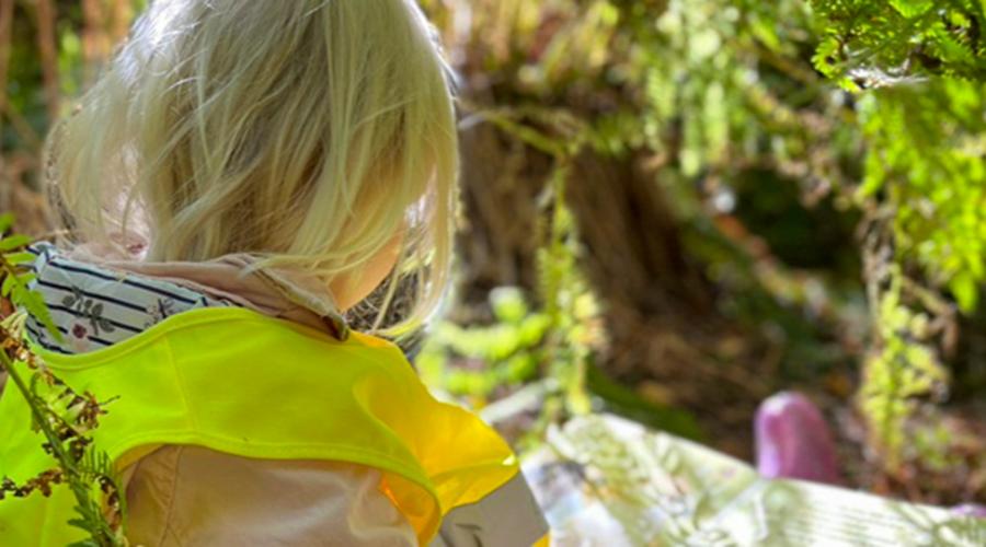 Flicka som läser bok i skogen.