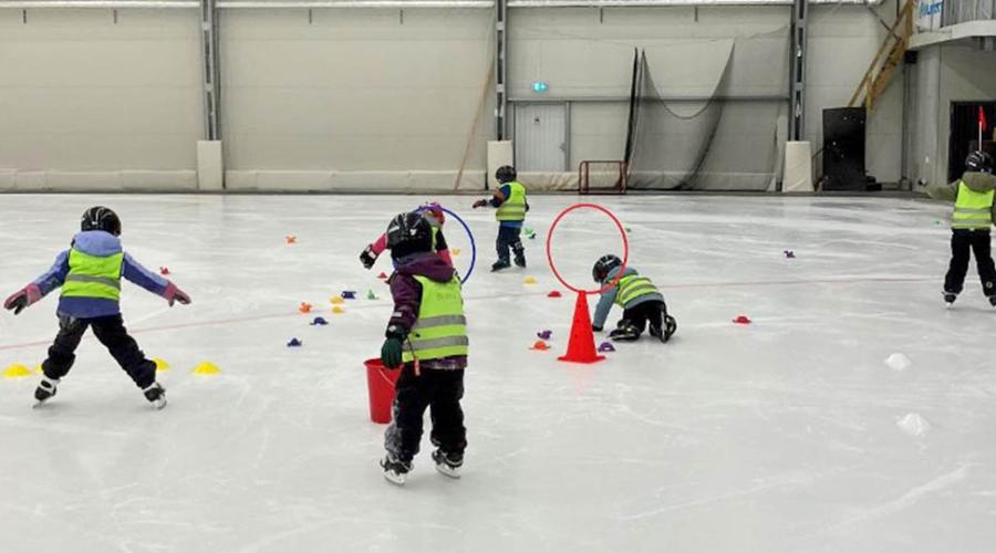Barn som åker skridskor i ishall.