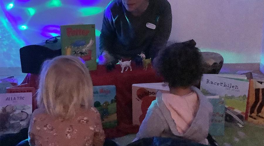 två barn läser bok med pedagog i magiskt rum