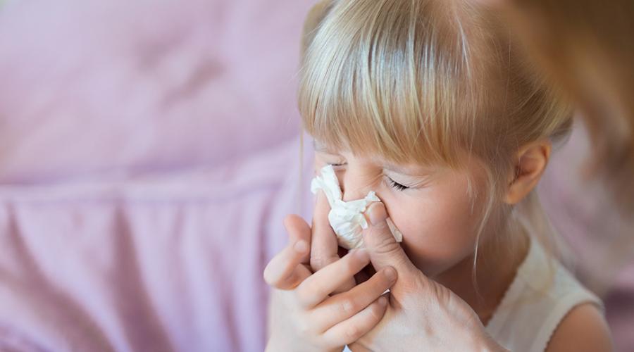 En kvinna snyter sin dotters rinnande näsa.