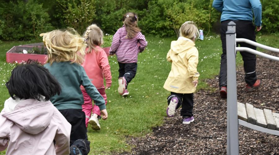 Fem barn och en pedagog på promenad i skogsmiljö.
