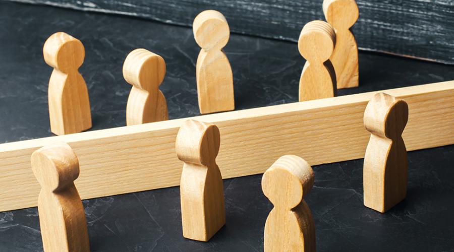 Två grupper träfigurer på var sin sida om ett staket.