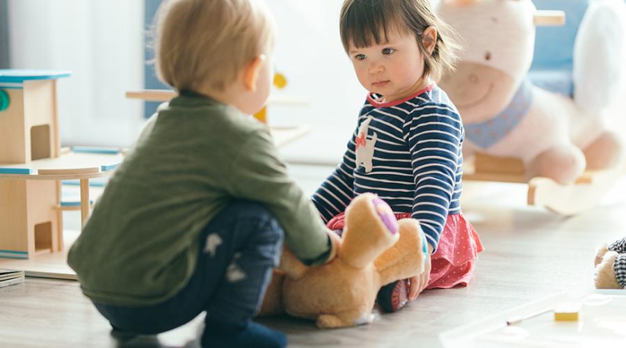 Två förskolebarn leker med varandra och leksaker.