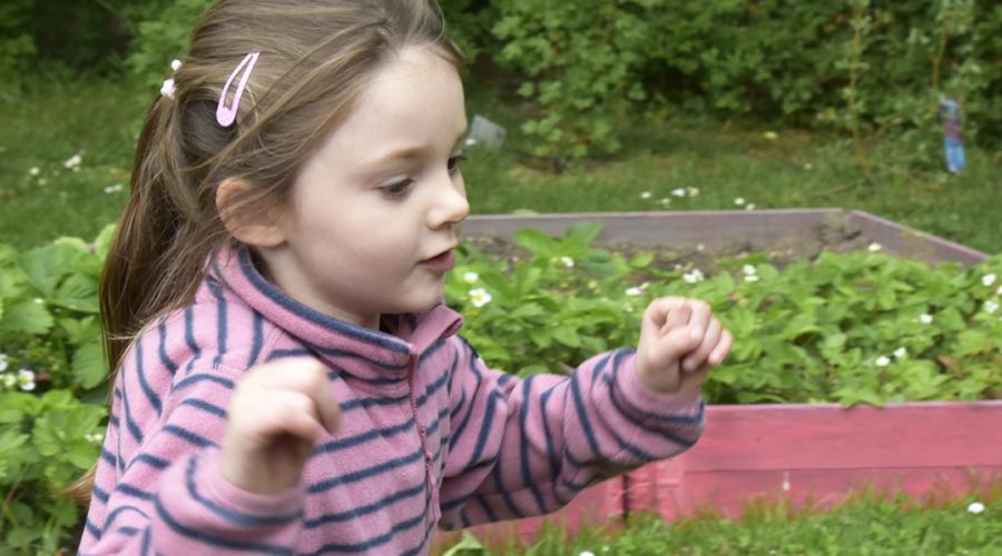 Flicka springer på förskolegården.