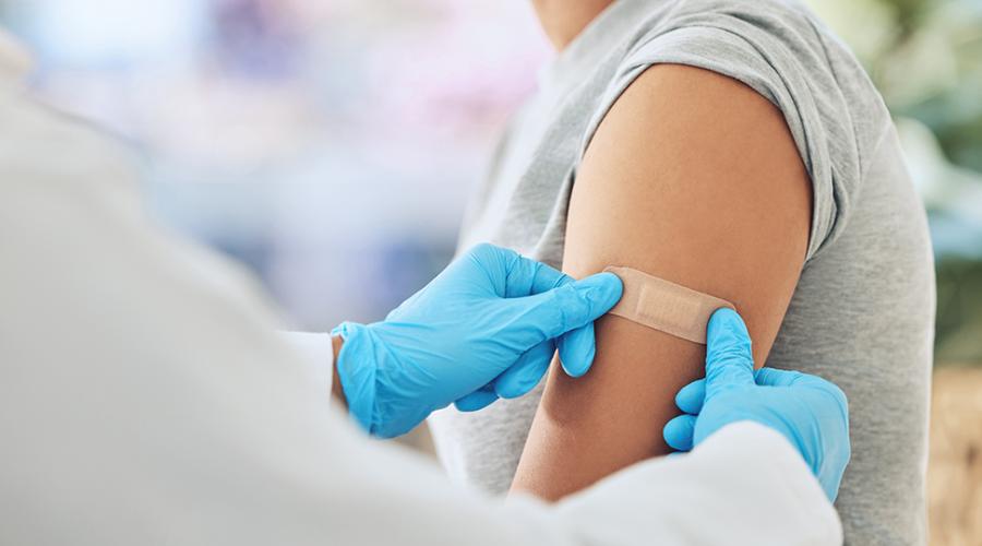 Sjuvårdspersonal sätter på ett plåster på en kvinnas överarm.