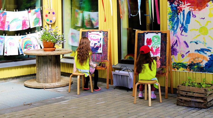 Förskolebarn målar vid stafflin i utomhusateljén.