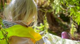 Flicka som läser bok i skogen.