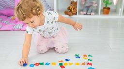 Ett barn som leker med bokstäver på golvet på förskolan.