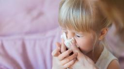 En kvinna snyter sin dotters rinnande näsa.