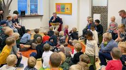Högläsning för stor grupp barn på biblioteket.