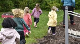 Fem barn och en pedagog på promenad i skogsmiljö.