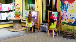 Förskolebarn målar vid stafflin i utomhusateljén.