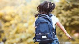 En flicka med ryggsäck springer.