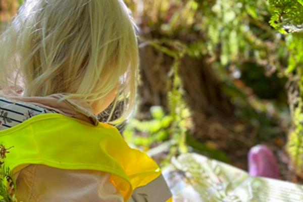 Flicka som läser bok i skogen.