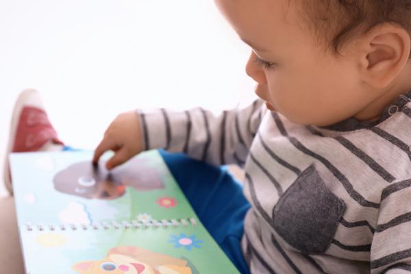 Ett förskolebarn med en uppslagen pekbok framför sig.