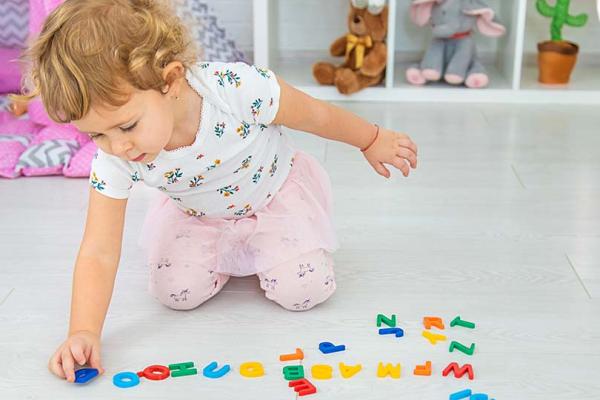 Ett barn som leker med bokstäver på golvet på förskolan.