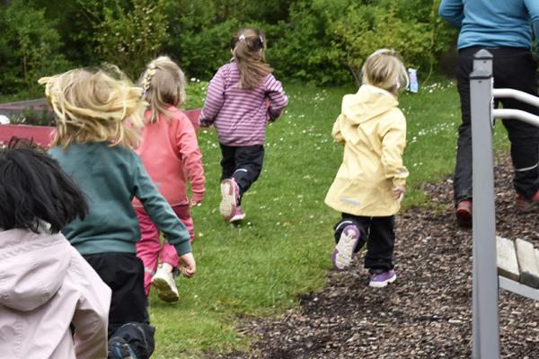 Fem barn och en pedagog på promenad i skogsmiljö.