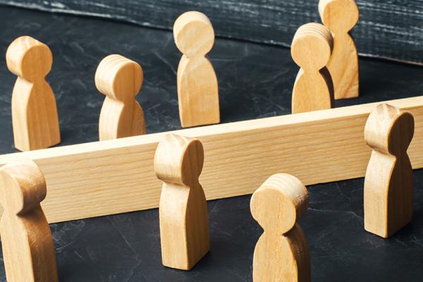 Två grupper träfigurer på var sin sida om ett staket.