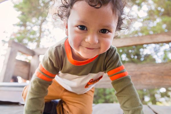 Glad tvåårig pojke i klätterställning.