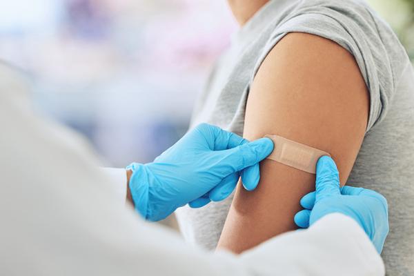 Sjuvårdspersonal sätter på ett plåster på en kvinnas överarm.