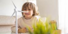 Pojke tittar på liten modell av ett vindkraftverk i inomhusmiljö.