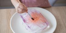 Hand som målar färg på ett isblock.