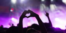 Två händer formar ett hjärta i ett publikhav på en musikfestival.