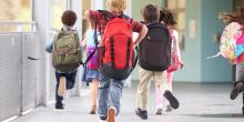 yngre skolbarn med skolväskor på väg till klassrummet