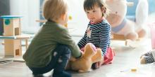 Två förskolebarn leker med varandra och leksaker.