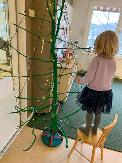 Flicka framför hembyggd julgran.