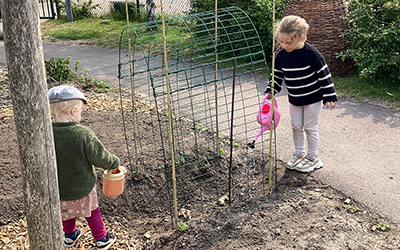 Två barn vattnar växter.