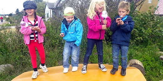 Fyra förskolebarn leker melodifestival utomhus.